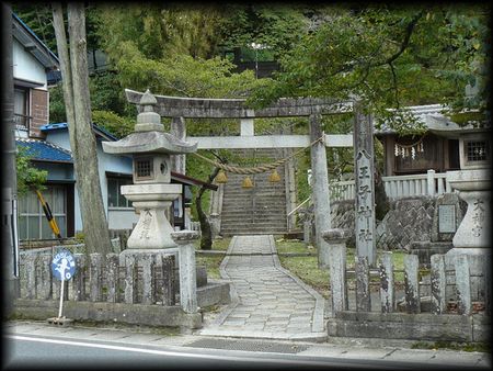 八王子神社境内正面に設けられた石造社号標ち石燈籠、その奥に建立されている石造鳥居