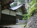 津島神社本殿とそれを囲う緑の木々と苔むした石垣